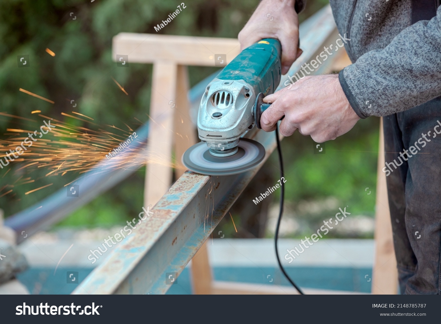 A man working with electric grinder tool on Steel beam. sparks flying. Electric grinding. Remove rust #2148785787