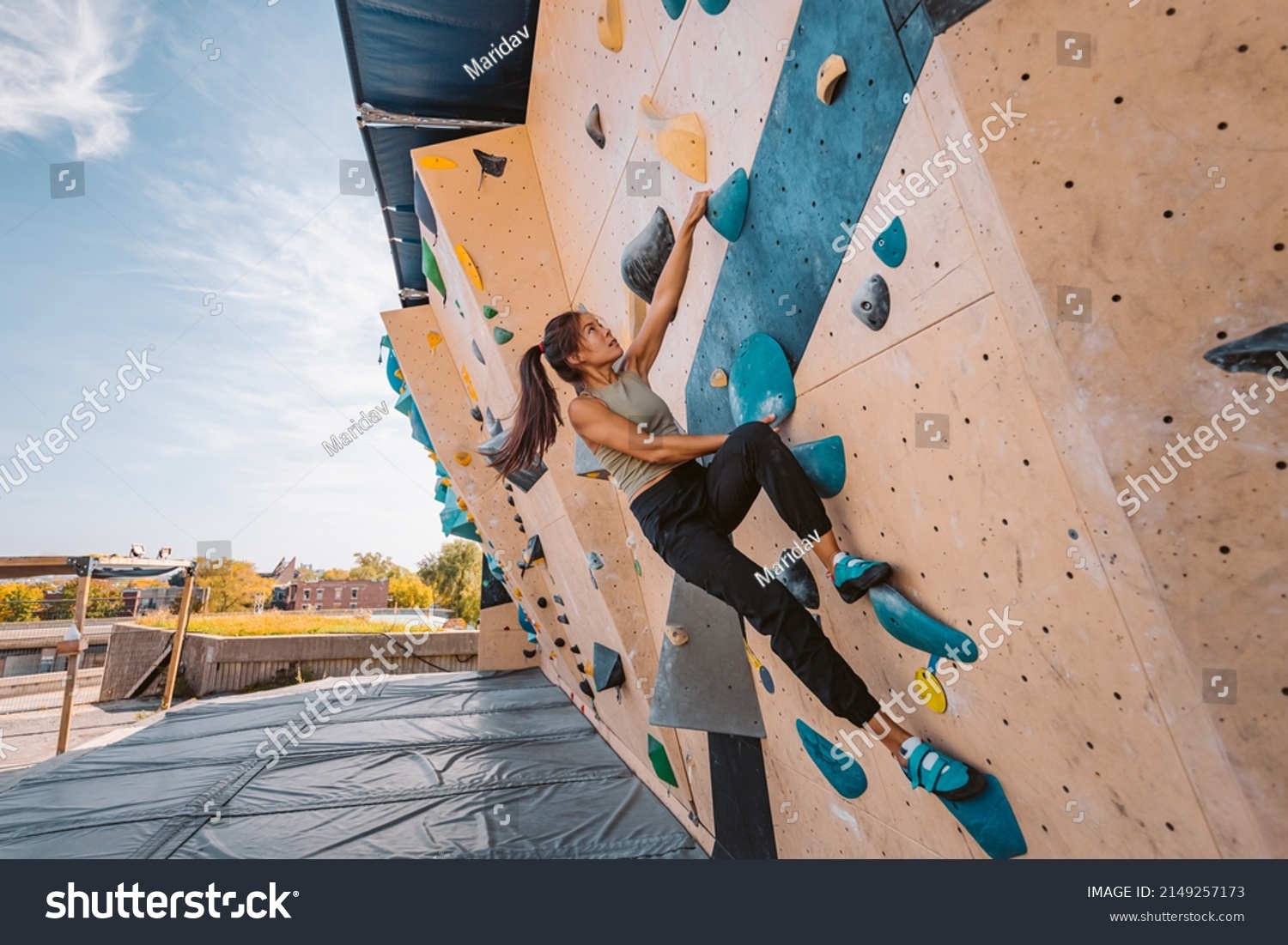 Asian climber woman climbing up outdoor bouldering wall at fitness gym. Fun active sport activity exercise outside #2149257173