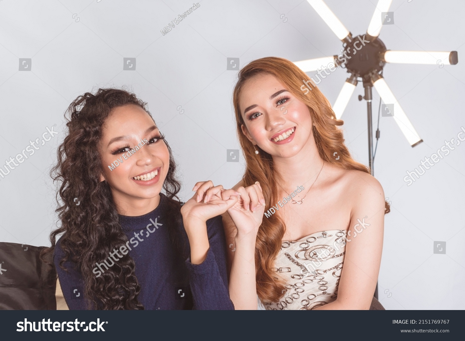Two lovely asian ladies making a pinky swear. Making a lighthearted pact. 2 models on location at a photographic studio. #2151769767