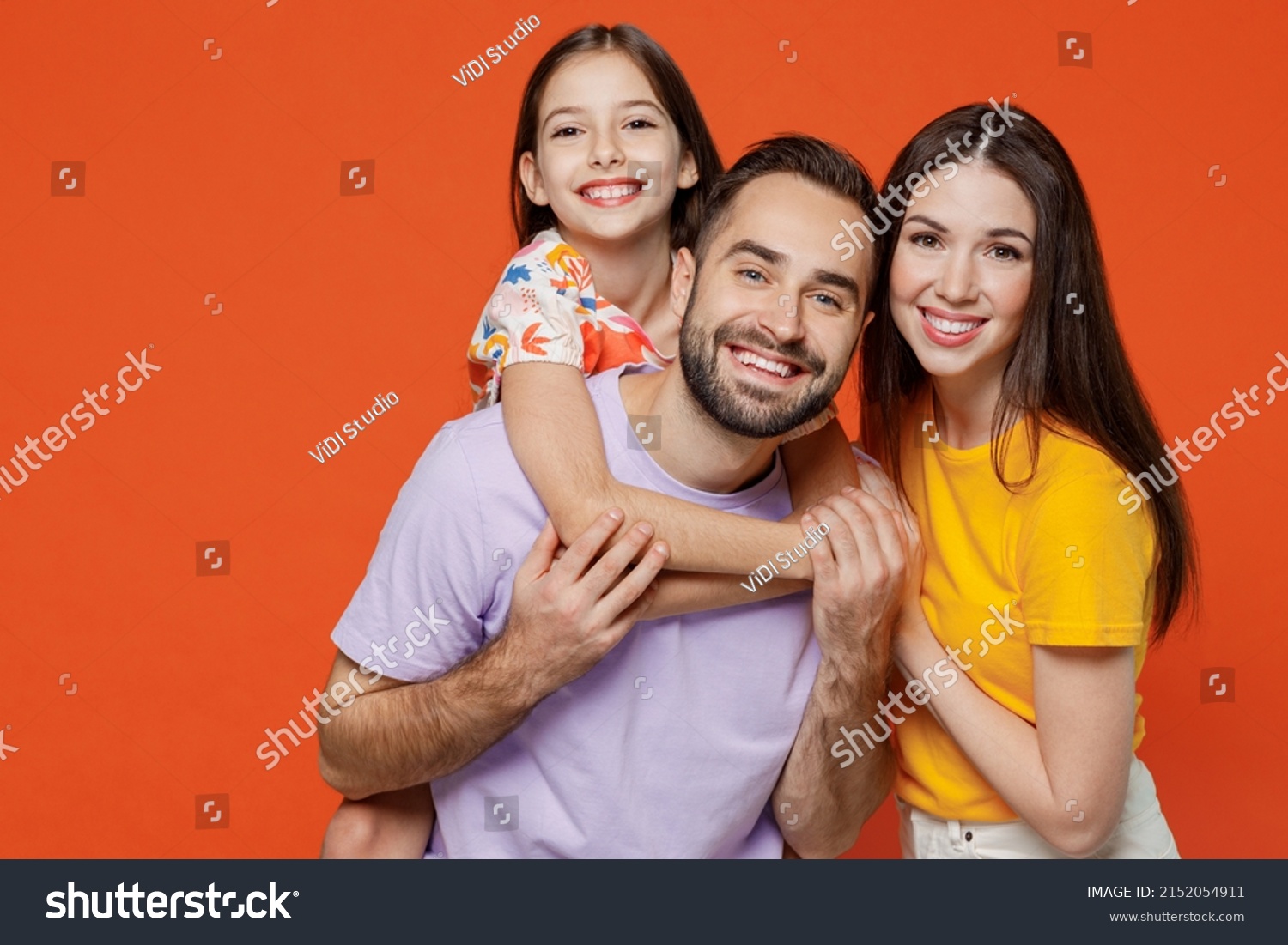 Young happy parents mom dad with child kid daughter teen girl wear basic t-shirts giving piggyback to daughter isolated on yellow background studio portrait. Family day parenthood childhood concept. #2152054911