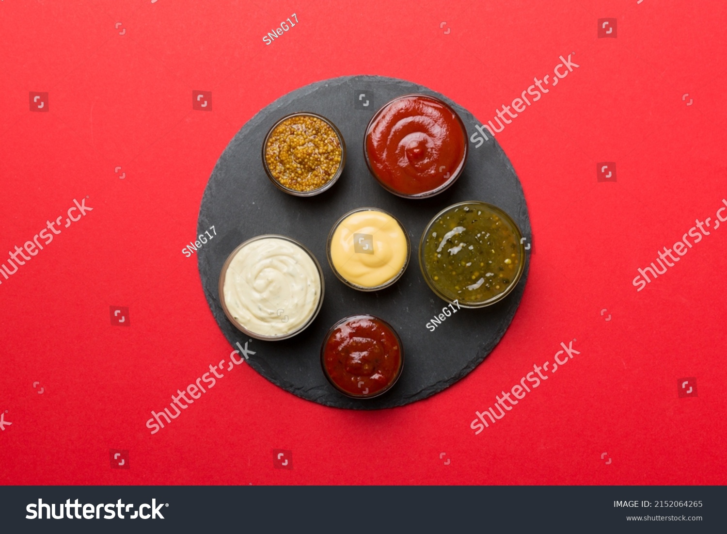 Different tasty sauces in bowls on plate on colored background. top view. #2152064265