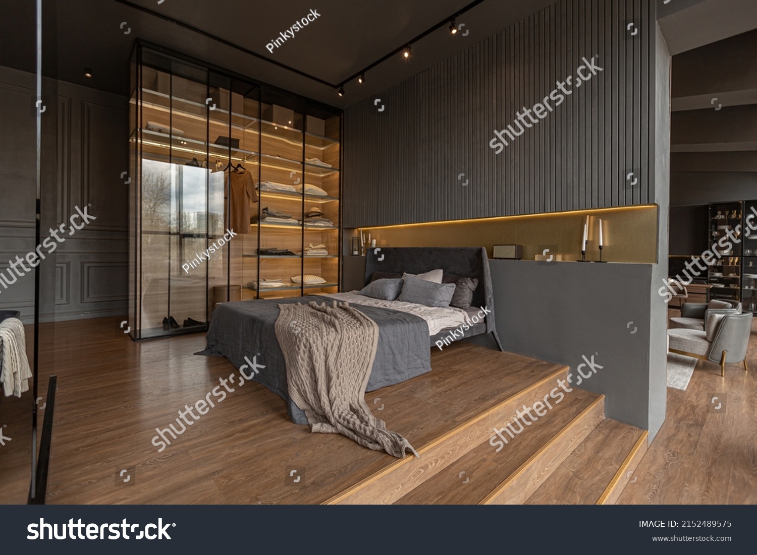 bedroom and freestanding bath behind a glass partition in a chic expensive interior of a luxury home with a dark modern design with wood trim and led light #2152489575