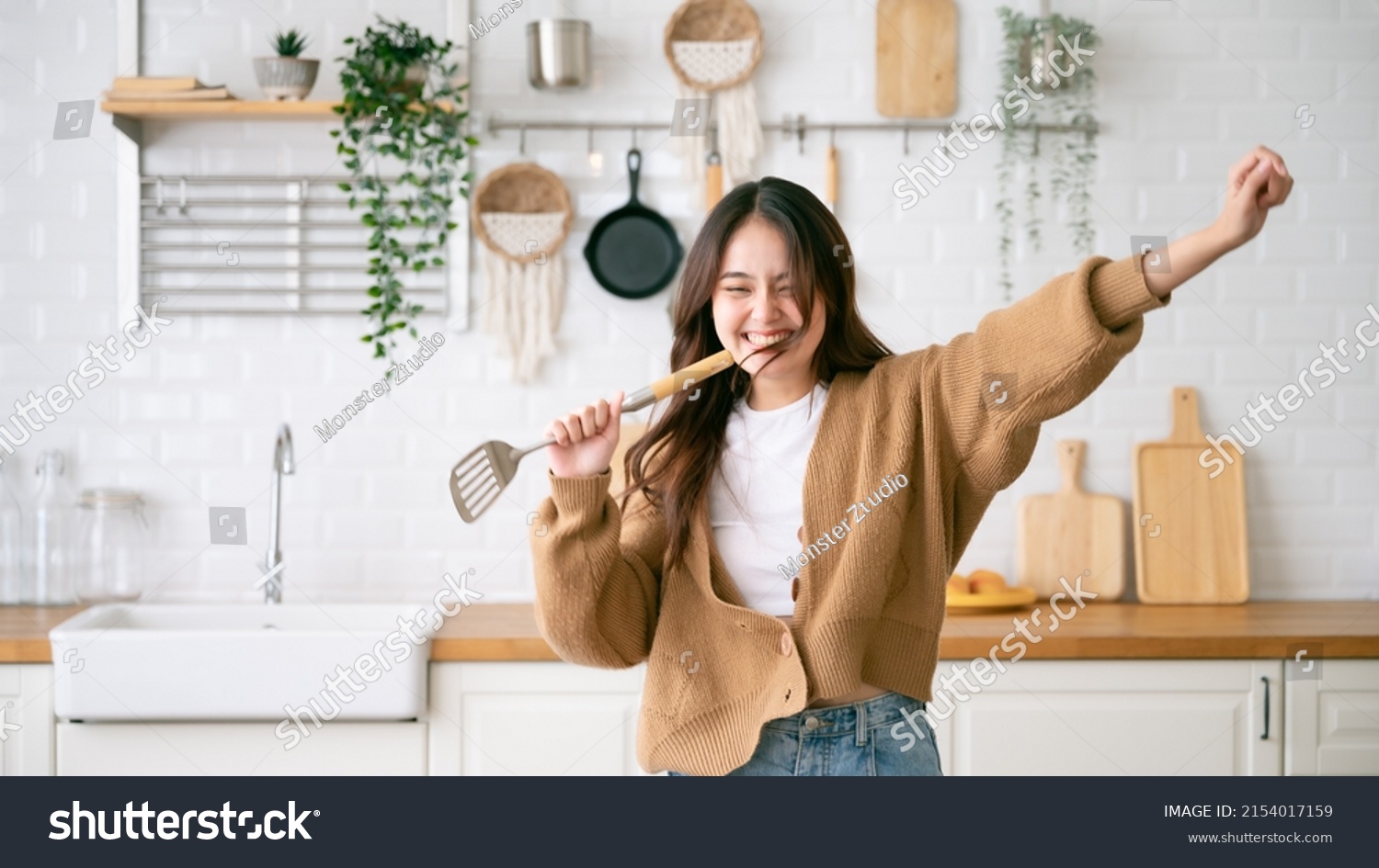 Asian young woman dancing in kitchen room. She happy and relaxing at free time on weekend #2154017159