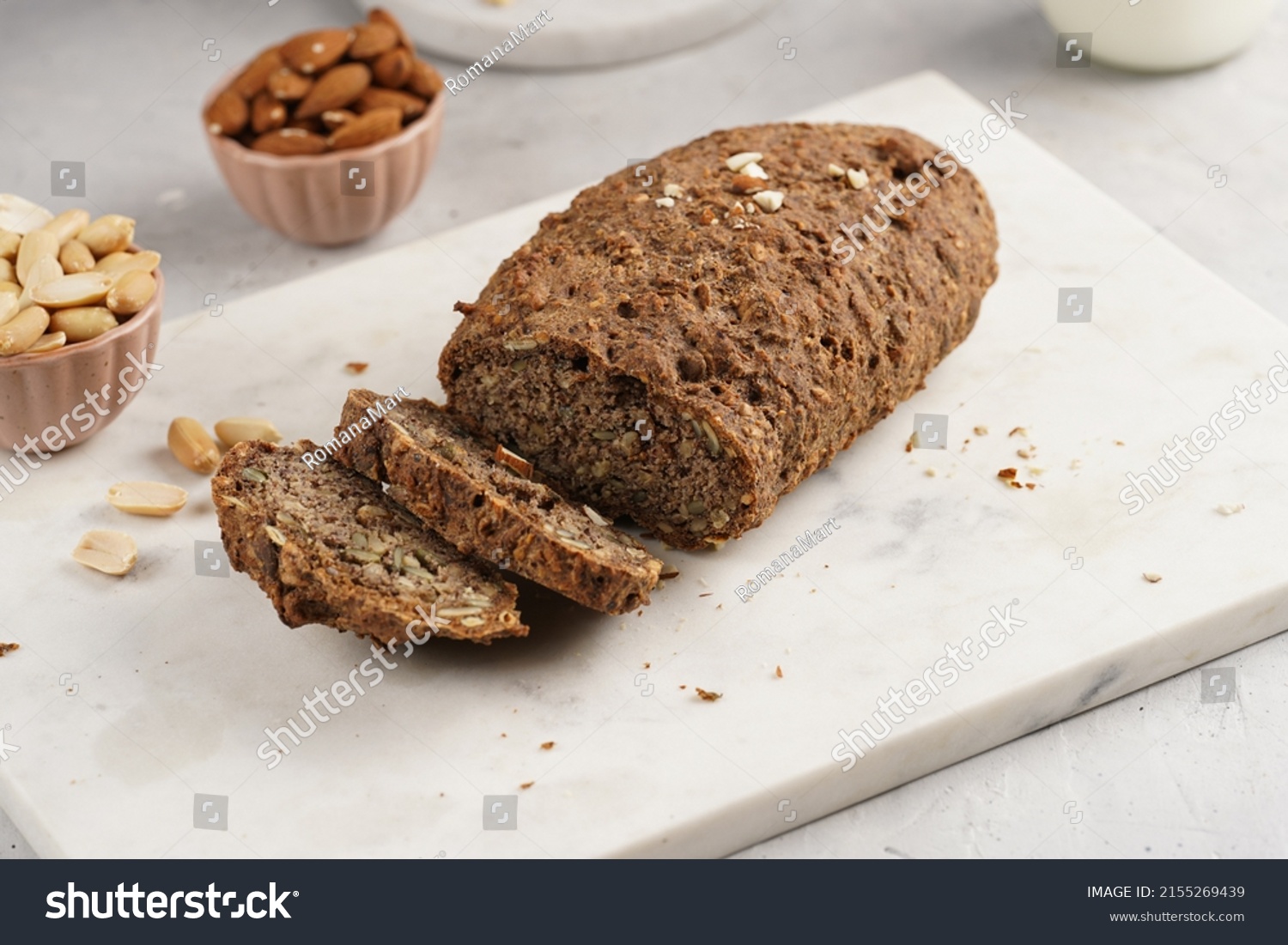 Homemade gluten-free and yeast-free buckwheat whole bread bread loaf with sunflower and pumkin seeds and nuts, cut in slices on white marble board #2155269439