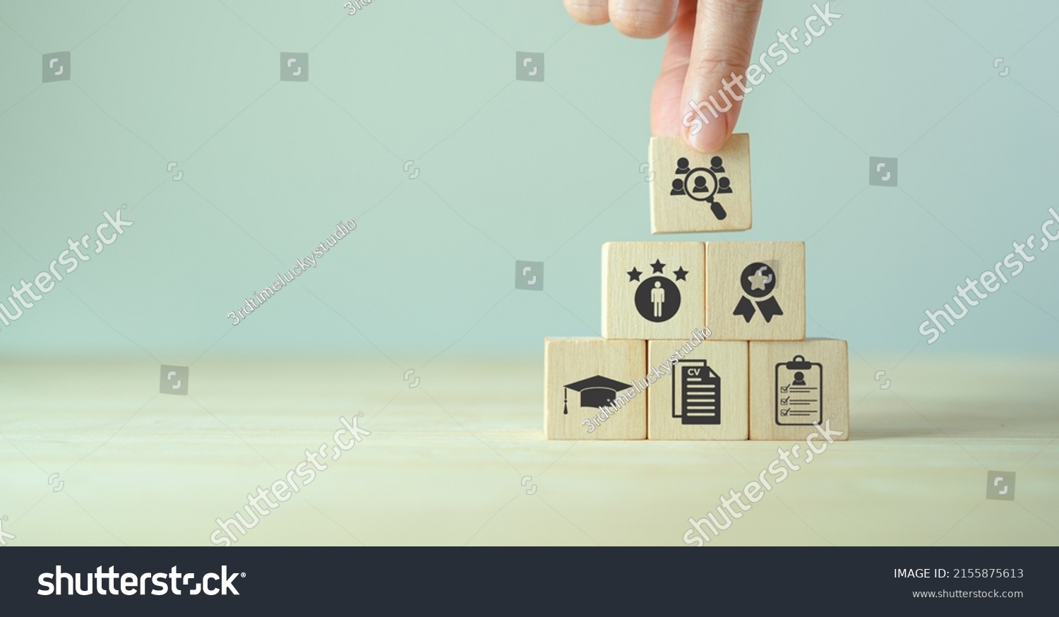 HRM and recruitment concept.  Job search, headhunting and recruitment process. Holding wooden cube with icons of education, qualification, cv, resume, skills and experience on smart grey background.  #2155875613
