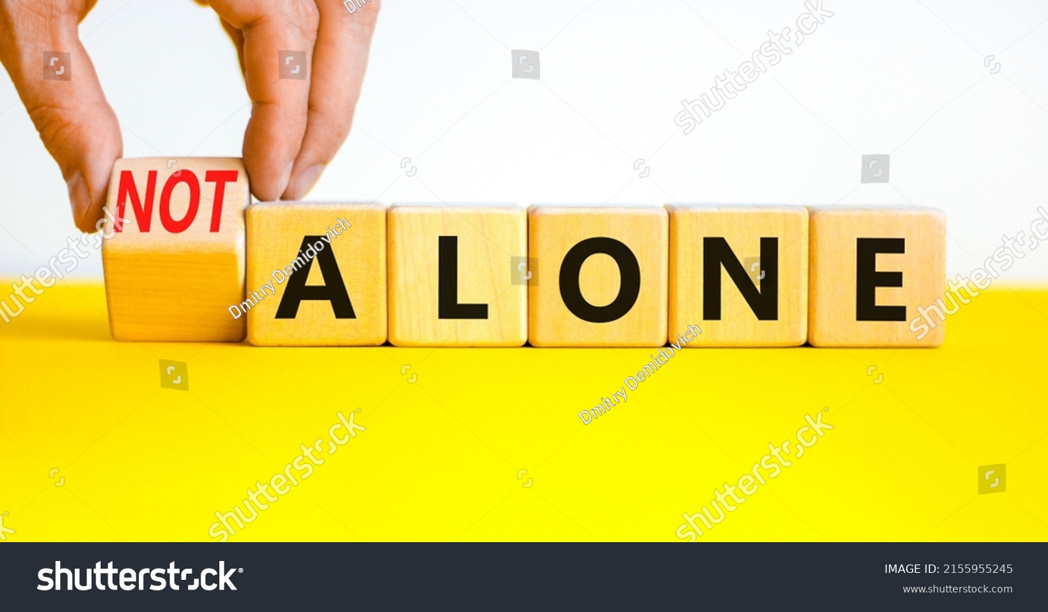 You are not alone symbol. Businessman turns wooden cubes and changes concept words alone to not alone. Beautiful white background. Business, support and you are not alone concept. Copy space. #2155955245