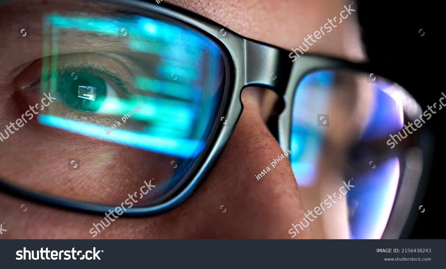 Focused developer coder wears glasses working on computer looking at programming code data cyber security digital tech reflecting in spectacles developing software program, focus on eye close up view. #2156438243