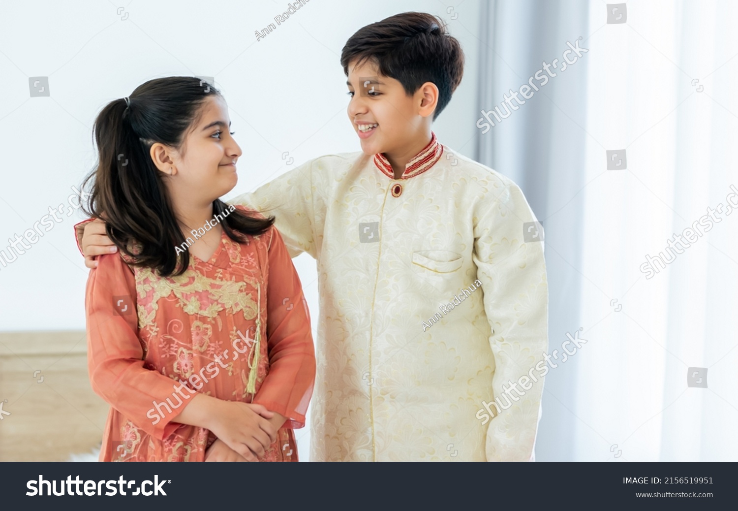 Portrait two people Indian siblings, brother, sister hugging with warmth, love, wearing traditional clothes, smiling with happiness in cozy indoor home. Family, Education, Lifestyle Concept #2156519951