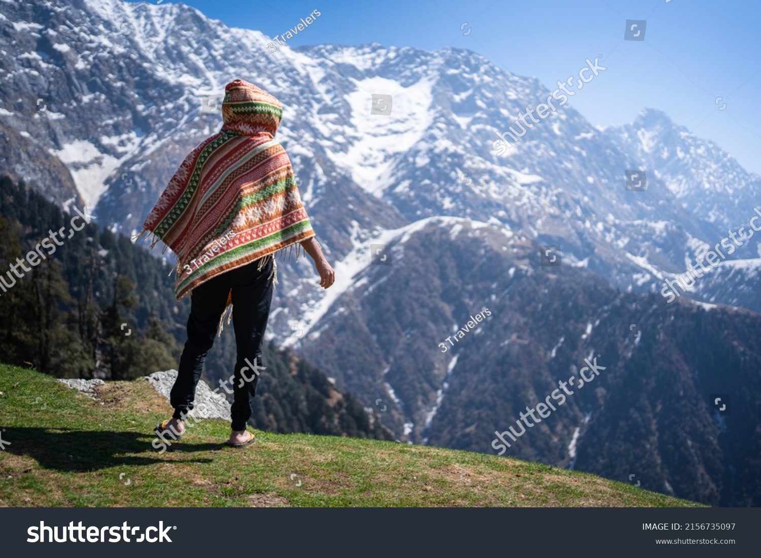 Hiker with local dress on the slope against the background of high snow-capped mountains of Triund Trek, Himachal Pradesh, India. #2156735097