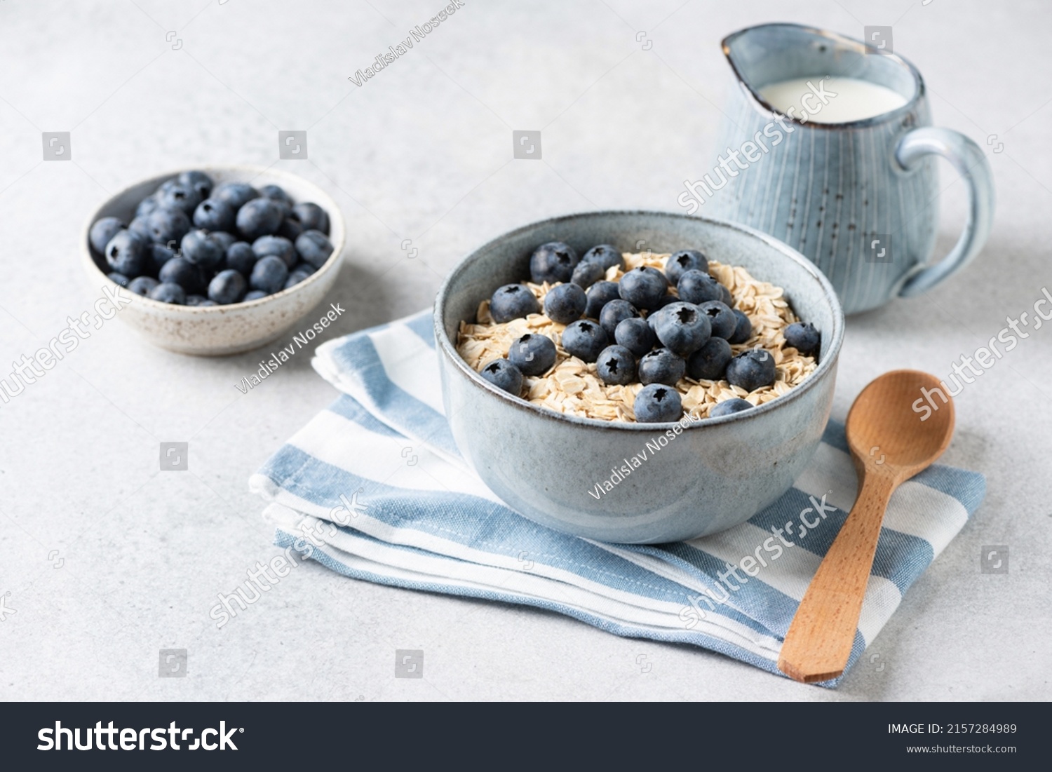 Uncooked oatmeal porridge with blueberries in bowl. Oat flakes, rolled oats. Breakfast meal concept #2157284989
