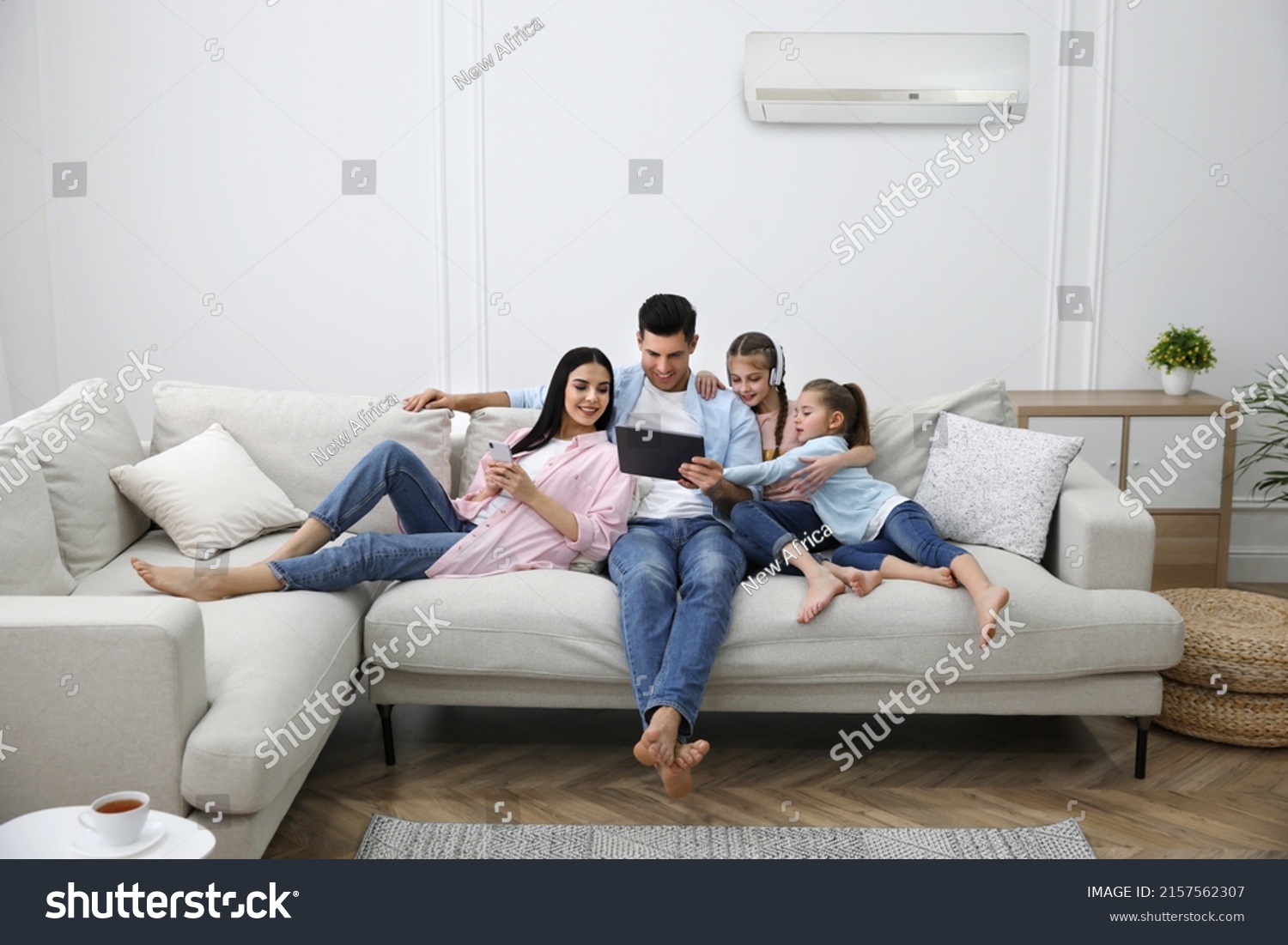 Happy family resting under air conditioner on white wall at home #2157562307
