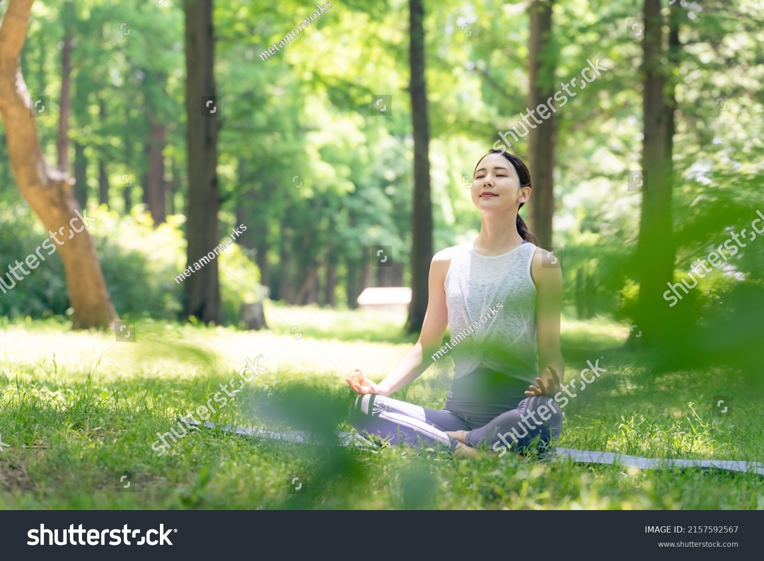 Asian woman meditating in the woods. Forest yoga. Mindfulness. #2157592567