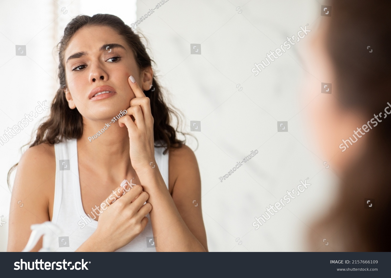 Skin Problem. Depressed Woman Touching Pimple On Face Looking At Mirror In Modern Bathroom. Facial Skin Issues, Medical Care And Treatment Concept. Selective Focus #2157666109