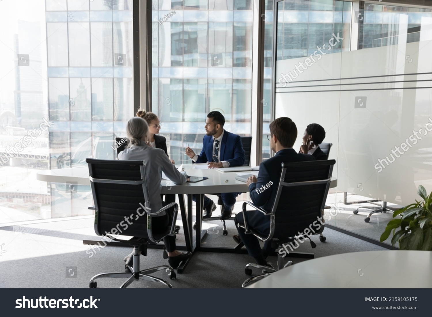 Serious team of professionals, five multi ethnic business people negotiating in modern boardroom, discuss project, consider contract terms and conditions, solve business. Formal meeting event concept #2159105175