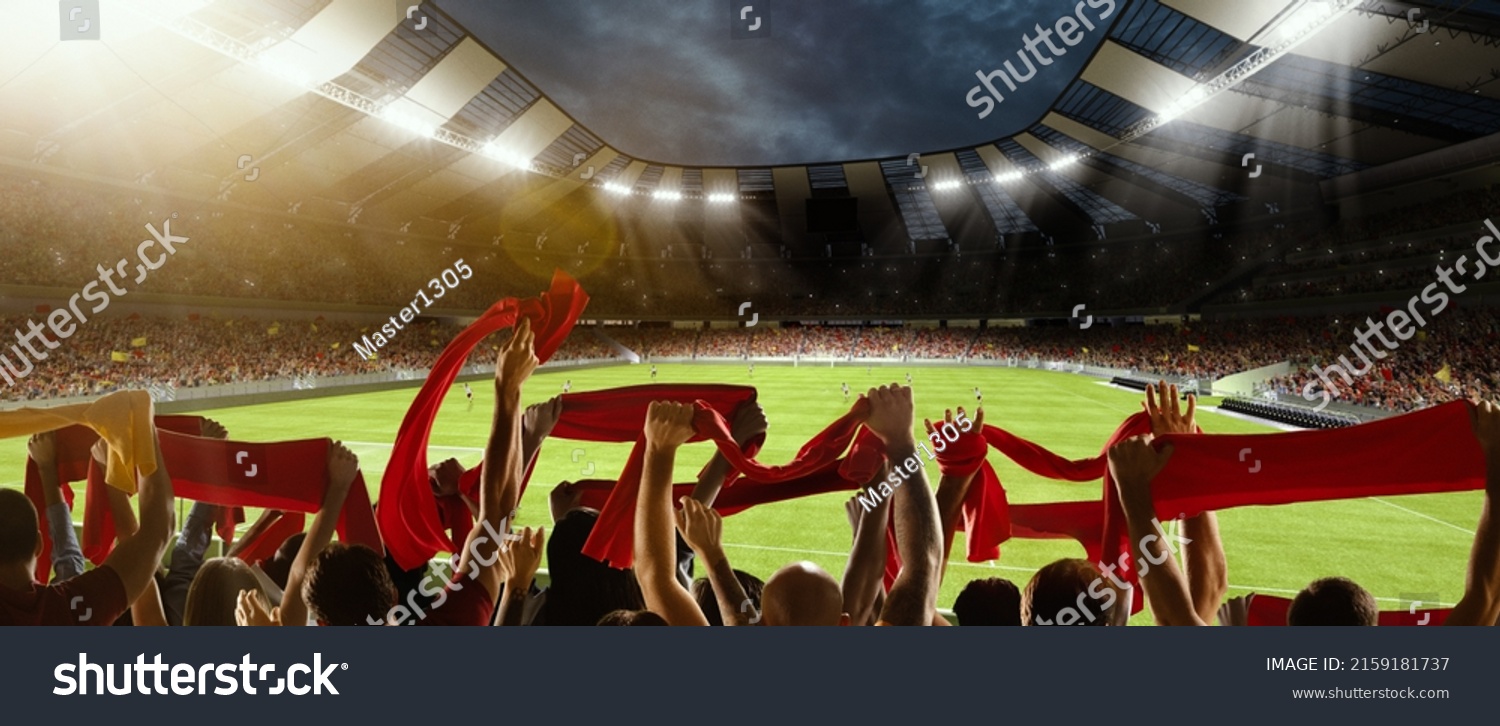 Win, victory of favourite team. Back view of football, soccer fans cheering their team with red scarfs at crowded stadium at evening time. Concept of sport, cup, world, event, competition #2159181737