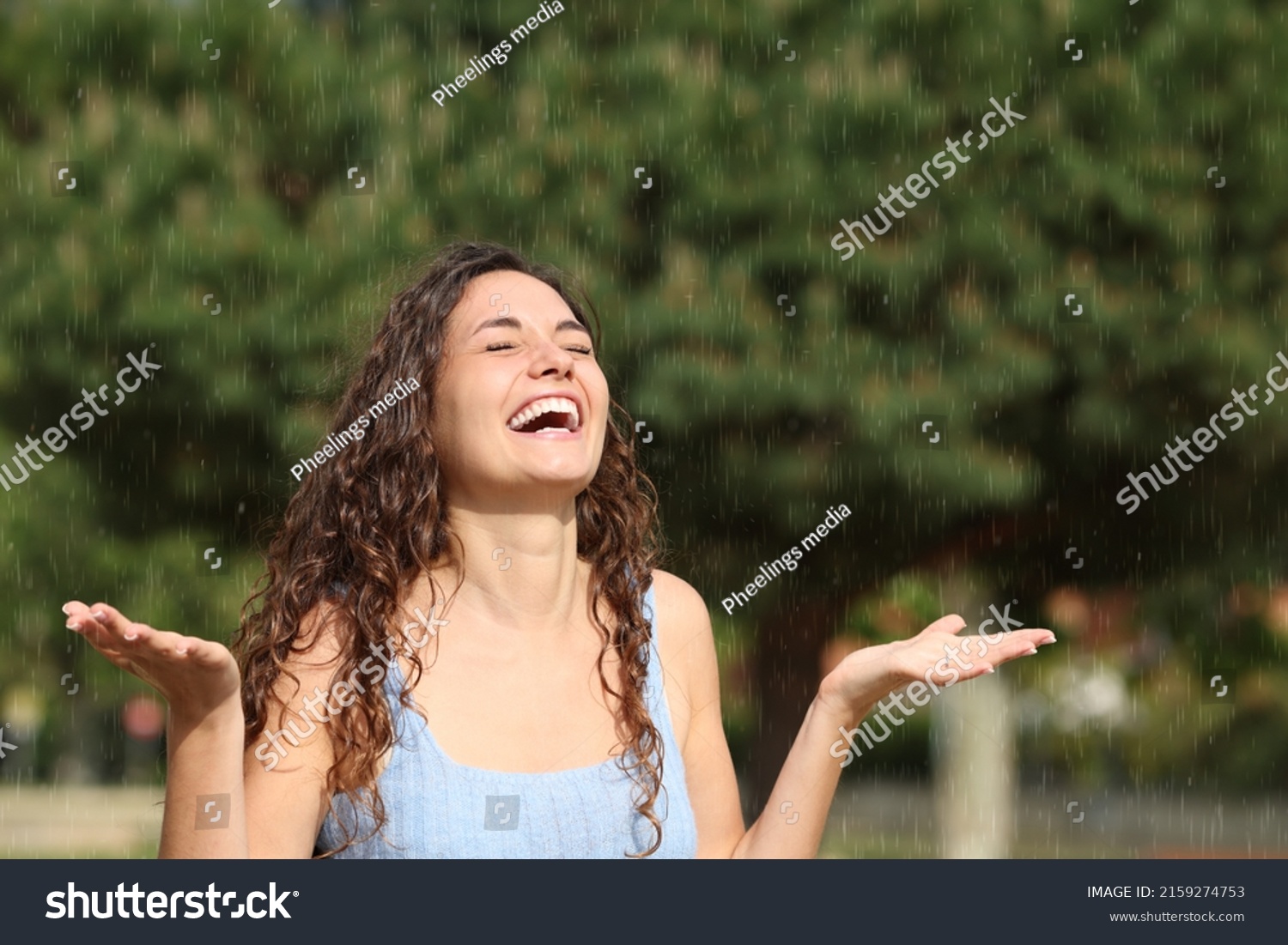 Happy woman laughing and enjoying under sudden rain in a sunny day #2159274753