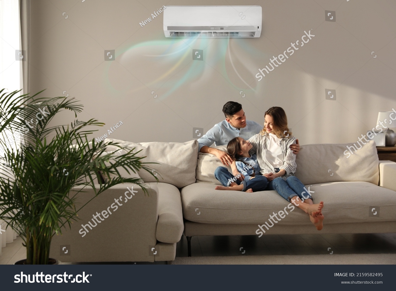 Happy family resting under air conditioner on beige wall at home #2159582495