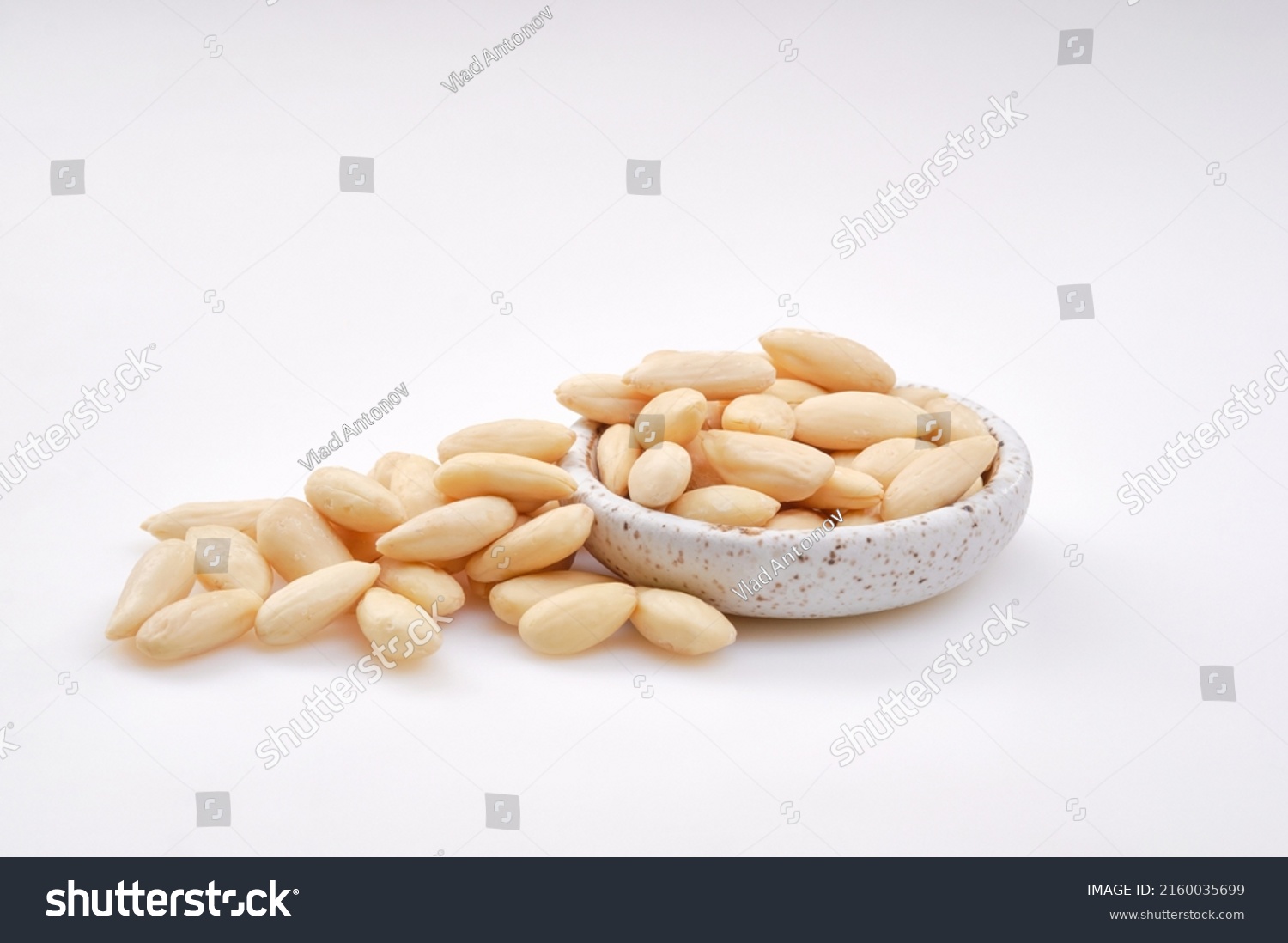 Pile of peeled or blanched almonds. White bowl of peeled whole almonds on white background. Shallow depth of field #2160035699
