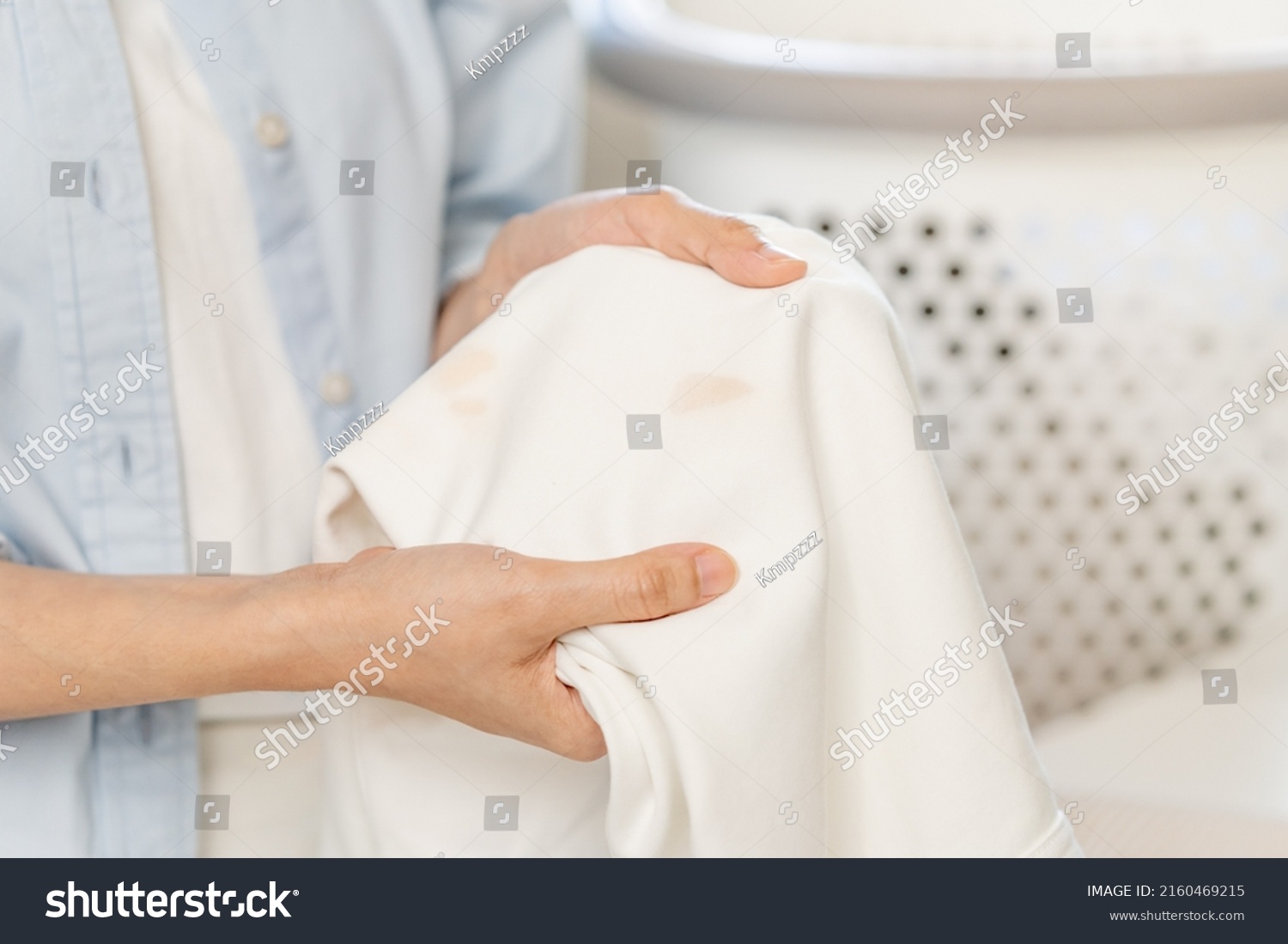 Housewife, asian young woman hand in holding shirt, showing making stain, spot dirty or smudge on clothes, dirt stains for cleaning before washing, making household working at home. Laundry and maid. #2160469215