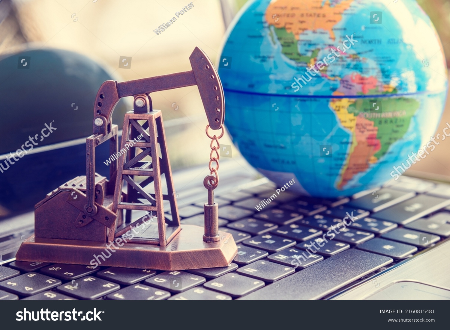 Petroleum and crude oil concept : Oil rig or a pumpjack and world globe on a laptop, depicting investment and development or production and manufacturing of global oil industry around the world. #2160815481
