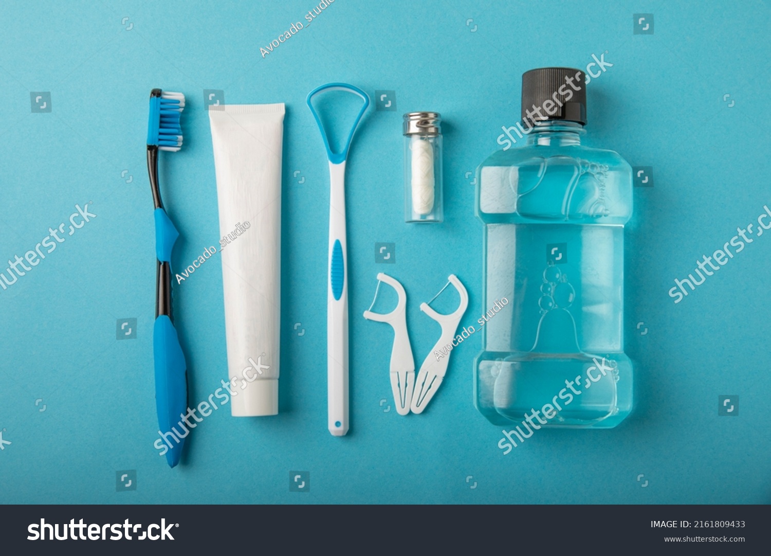 Toothbrush, tongue cleaner, floss, toothpaste tube and mouthwash on blue background with copy space. Flat lay. Dental hygiene. Oral care kit. Dentist concept. #2161809433