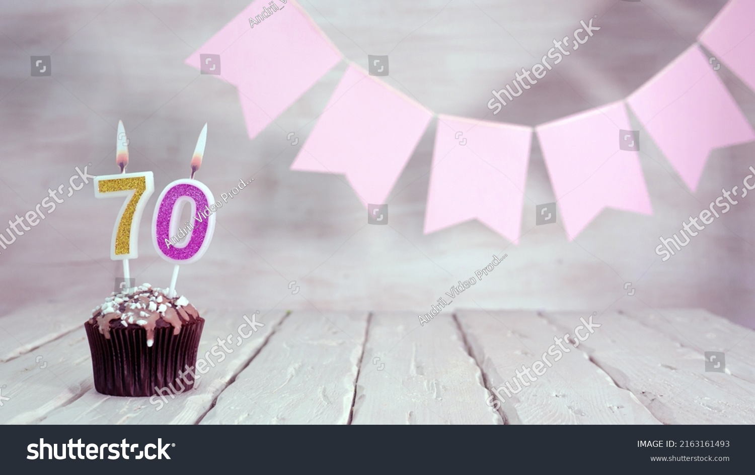 Birthday number 70. Festive background for a girl or woman with a muffin and candles burning pink in pastel colors with decorations for any holiday, copy space, women's gift boxes, place for text. #2163161493