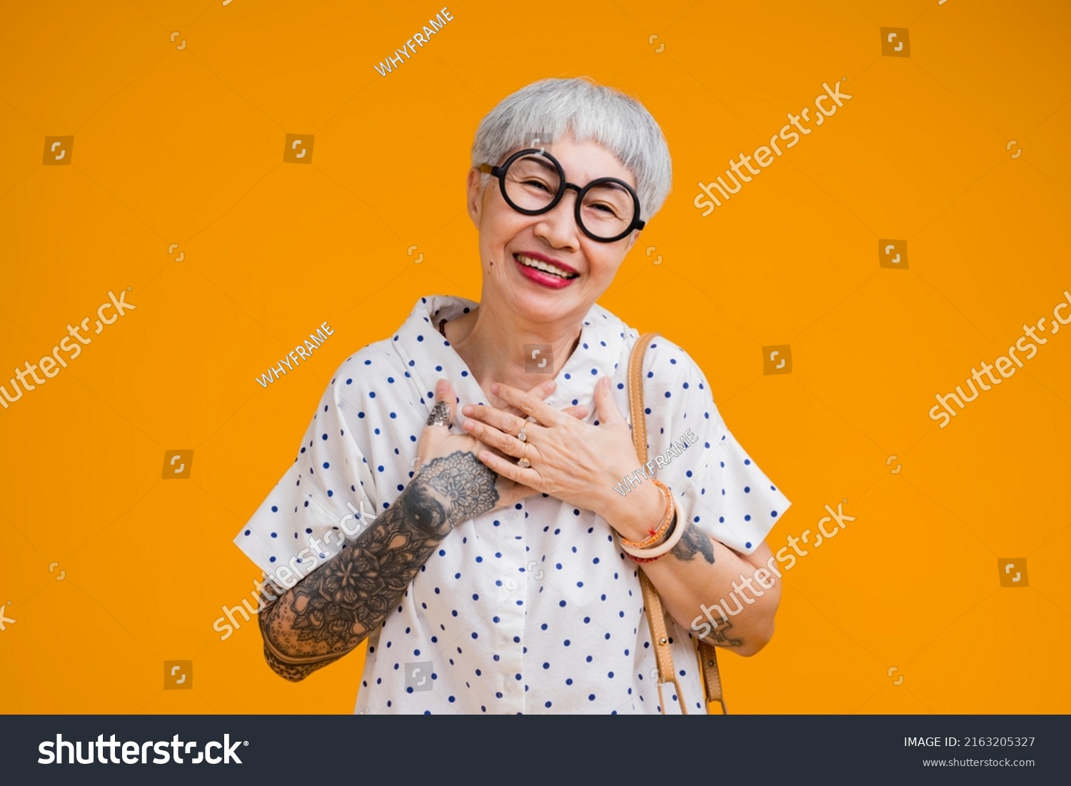 Portrait of attractive funky asian tattoo cheerful grey-haired elder old senior woman touching her chest isolated over yellow pastel background color,surprise and over exited feeling expression #2163205327