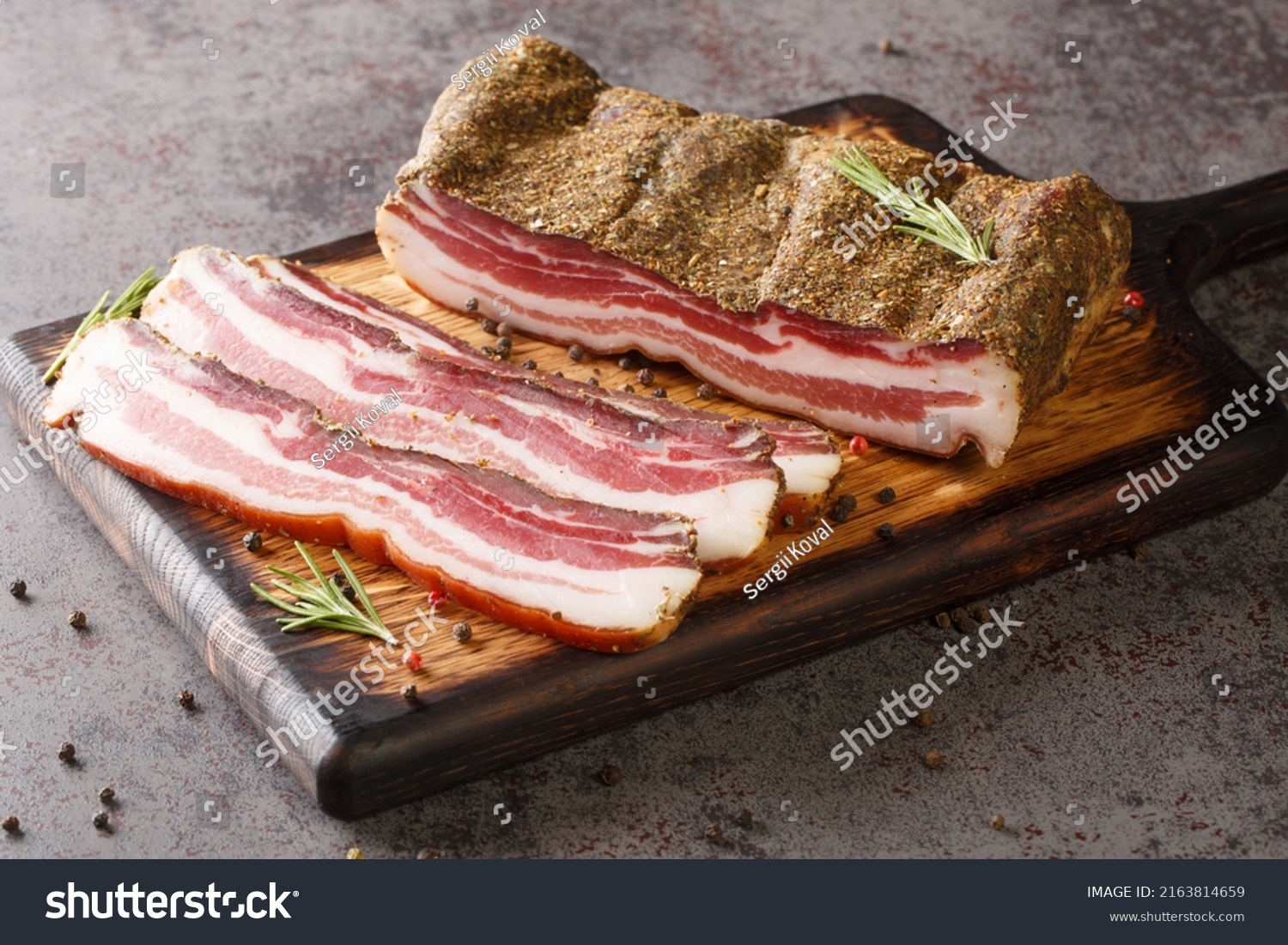 Pancetta Italian is a salt cured pork belly salume closeup on the wooden board on the table. Horizontal #2163814659
