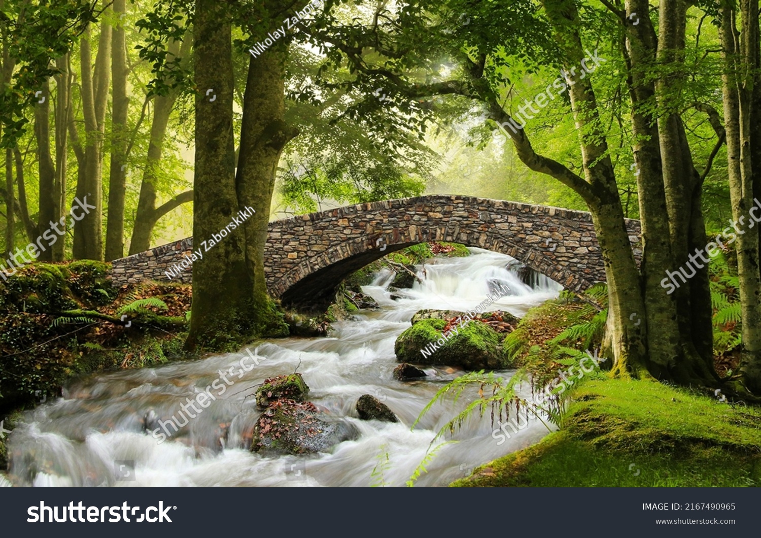 Stone bridge over a stormy stream in the forest. Forest stream bridge. Bridge over forest stream. Forest stream flowinf under stone bridge #2167490965