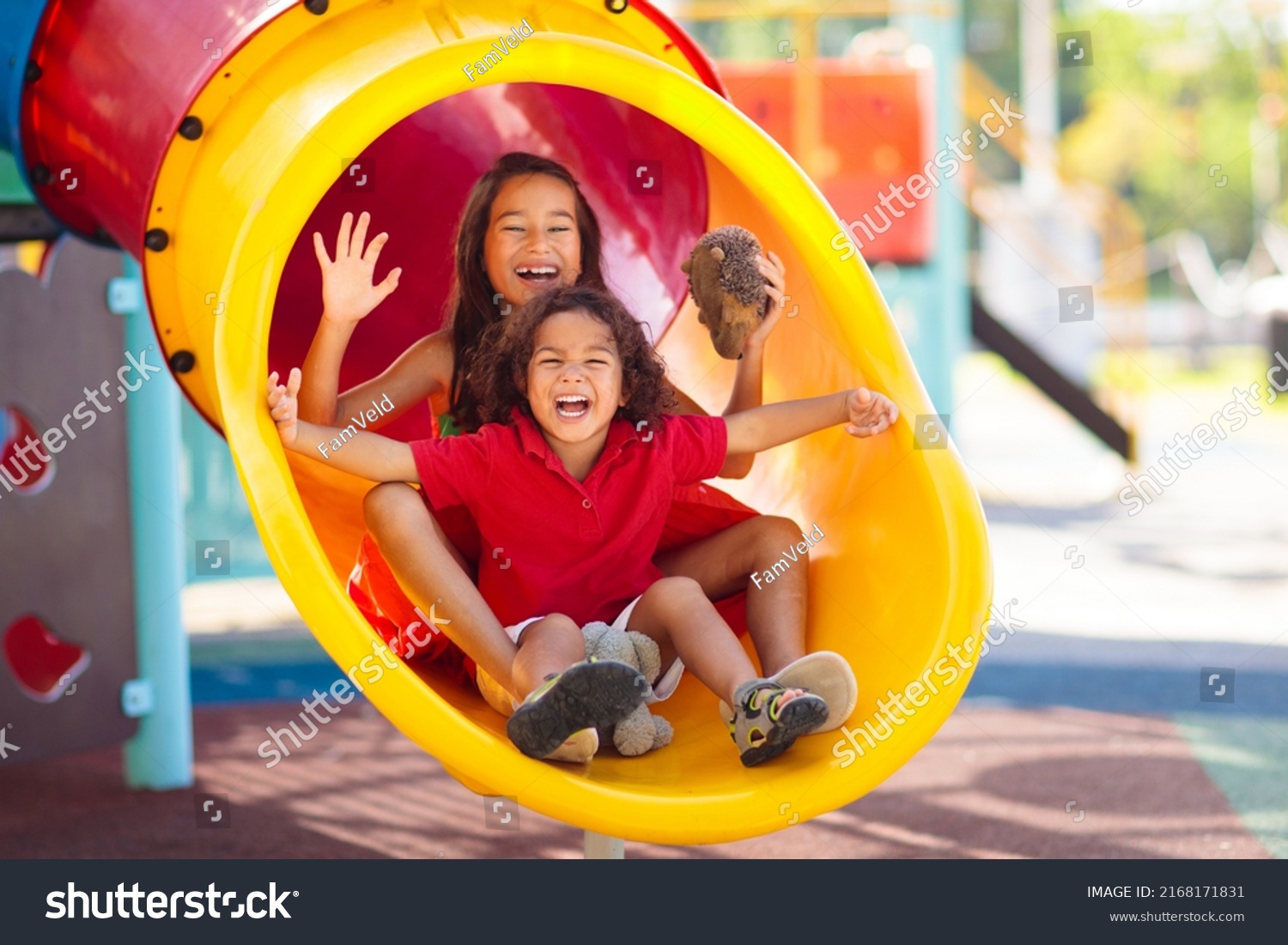 Kids on playground. Children play outdoor on school yard slide. Healthy activity. Summer vacation fun. Child playing in sunny park. Kid having fun on colorful slide. #2168171831