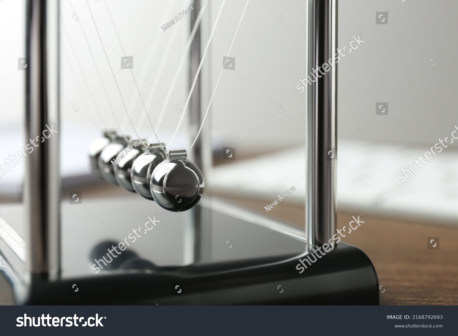 Newton's cradle on wooden table, closeup. Physics law of energy conservation #2168792693
