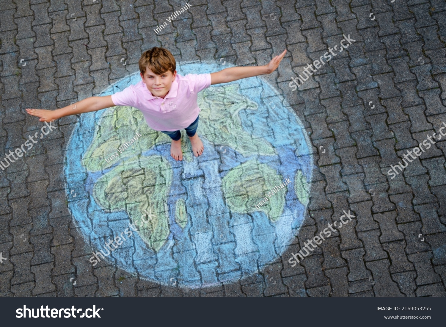 Little school boy with earth globe painting with colorful chalks on ground. Positive kid child. Happy earth day concept. Creation of children for saving world, environment and ecology. #2169053255