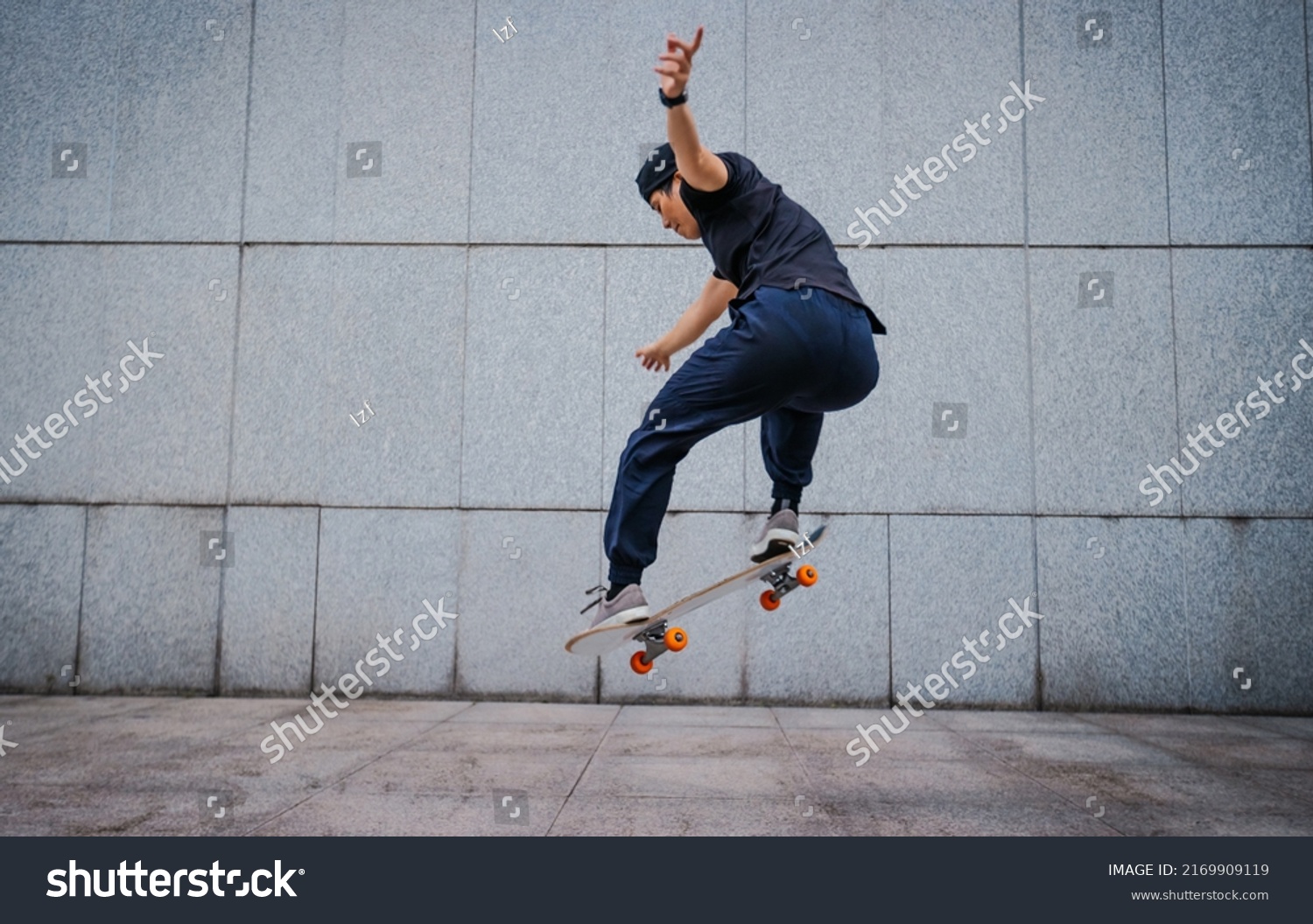 Asian woman skateboarder skateboarding in modern city #2169909119