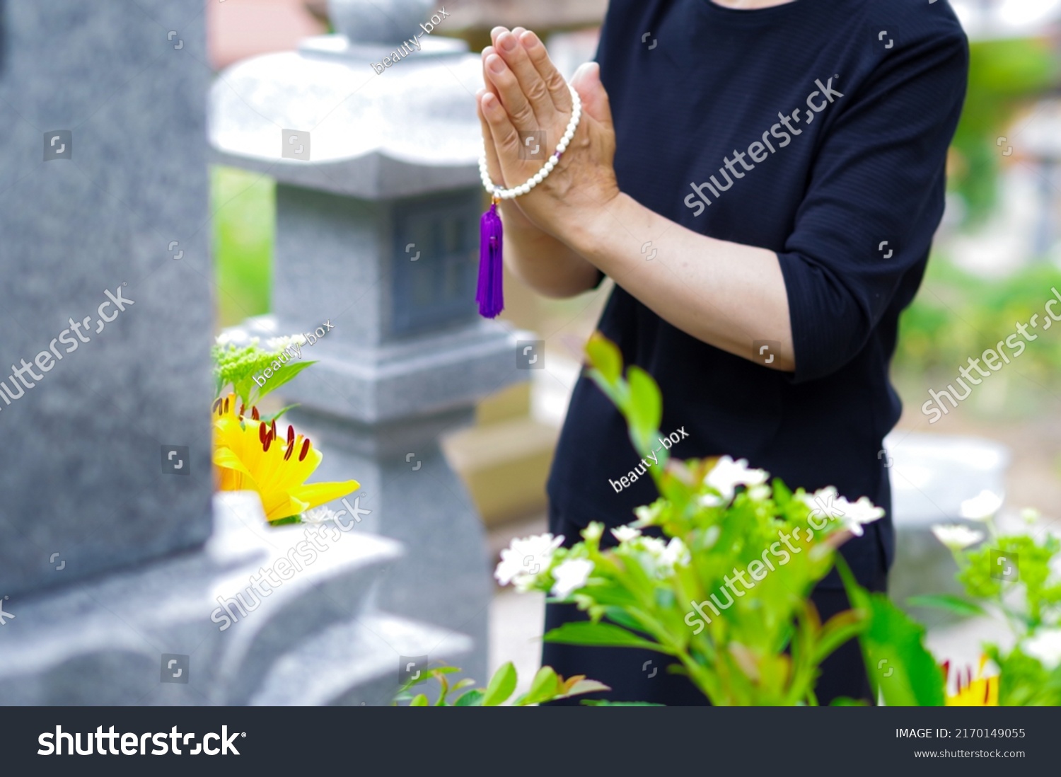 A Japanese woman putting her hands together at the grave, the style of visiting a Japanese grave #2170149055