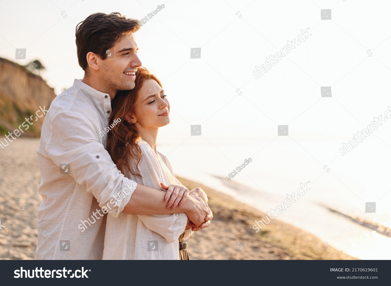 Close up profile happy satisfied smiling young couple two friends family man woman 20s in white clothes hug rest together at sunrise over sea beach ocean outdoor seaside in summer day sunset evening. #2170619601