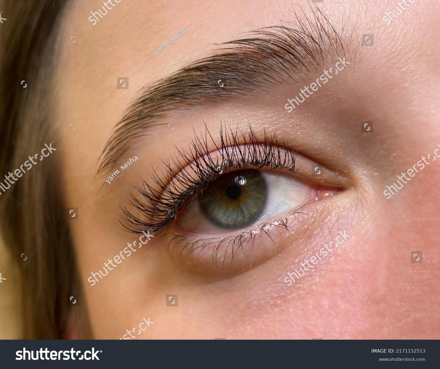 The procedure of classical eyelash extension. Beautiful female eyes close-up with long eyelashes #2171152513