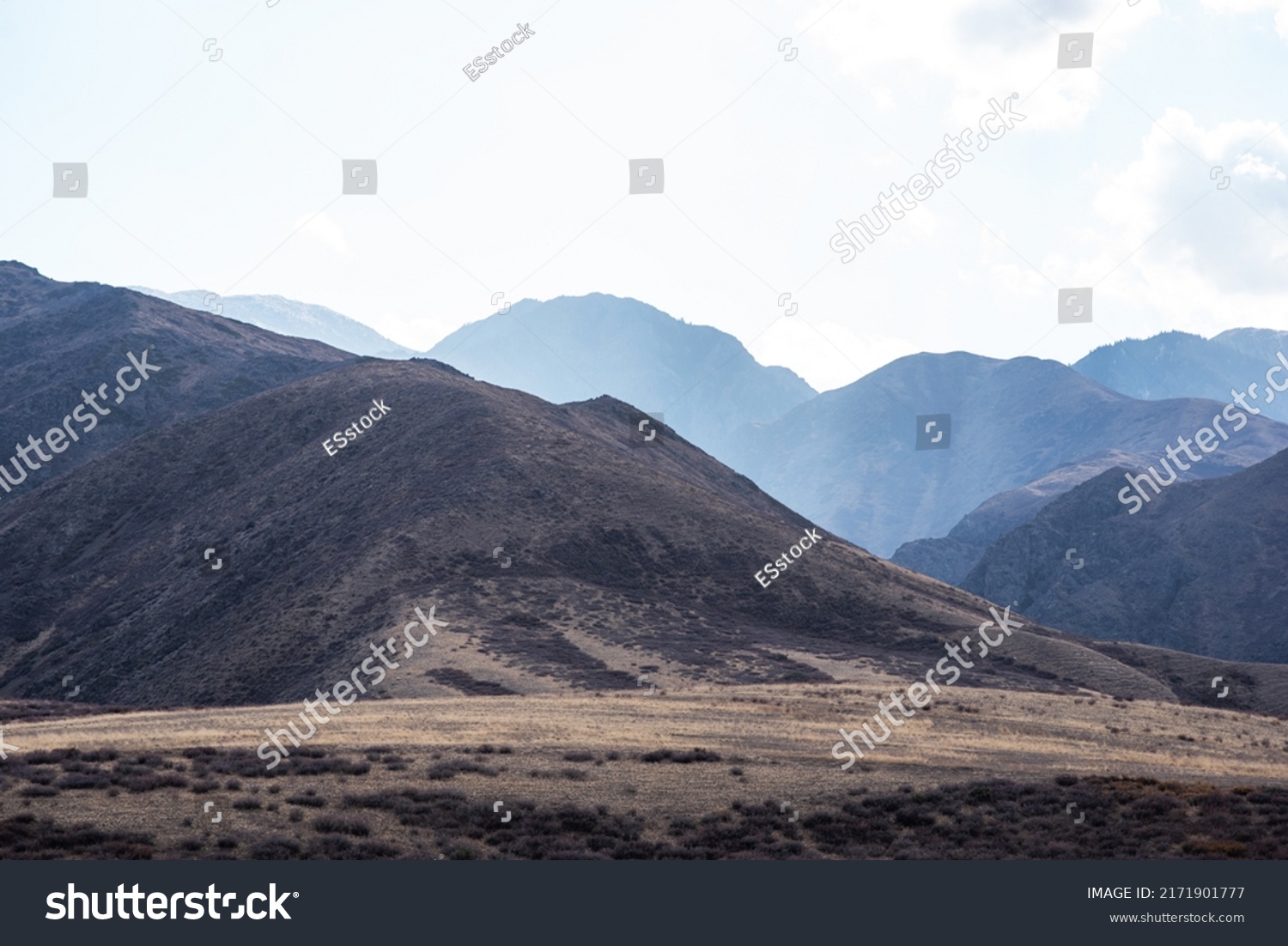 Unusual mountain landscape on a dull autumn day. Remote foothill areas in northern China. Dry grassy fields and hills. Natural background. Exploration of new places, travel to remote locations. #2171901777