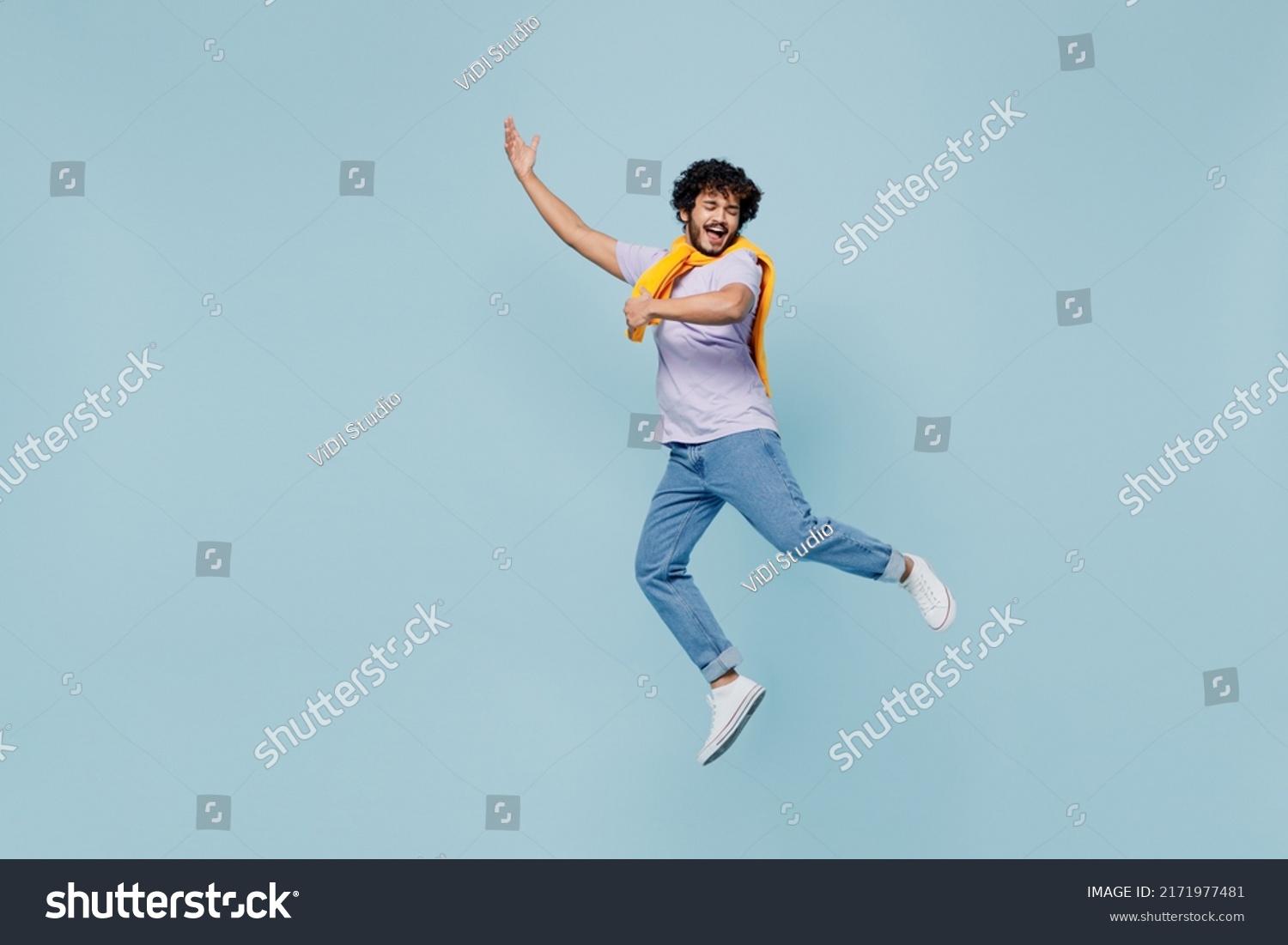 Full size body length amazing happy young bearded Indian man 20s years old wears white t-shirt singing song dreaming like playing guitar isolated on plain pastel light blue background studio portrait #2171977481