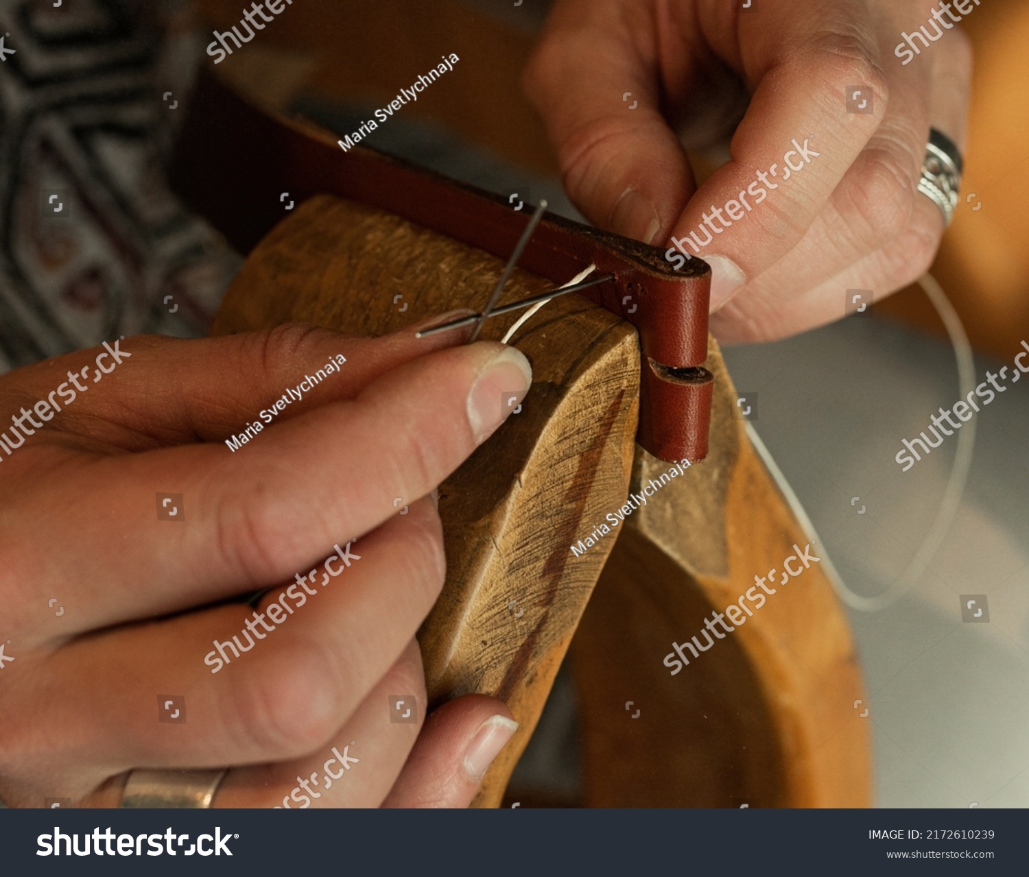 Handmade. the girl sews a leather belt in the workshop. Wooden machine. Atmospheric photo. Close up #2172610239