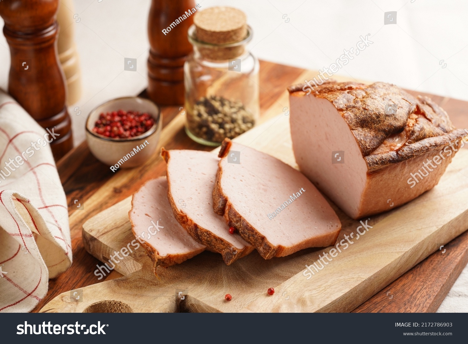 Traditional oven baked bavarian meal leberkäse sliced - meat dish made of corned beef, pork and bacon, finely ground and bakes as a bread loaf, on wooden board on dark wooden table with spices #2172786903