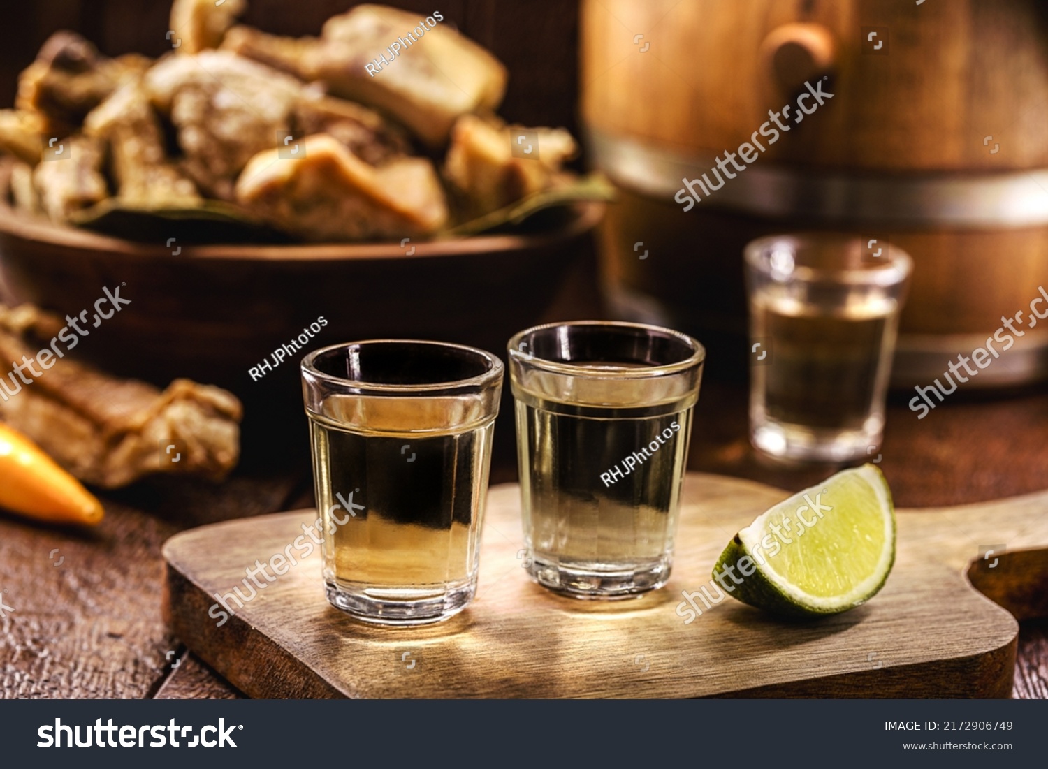 Cachaça, pinga, cana or caninha is the sugar cane brandy, a typical drink from Brazil, with a crackling appetizer in the background #2172906749