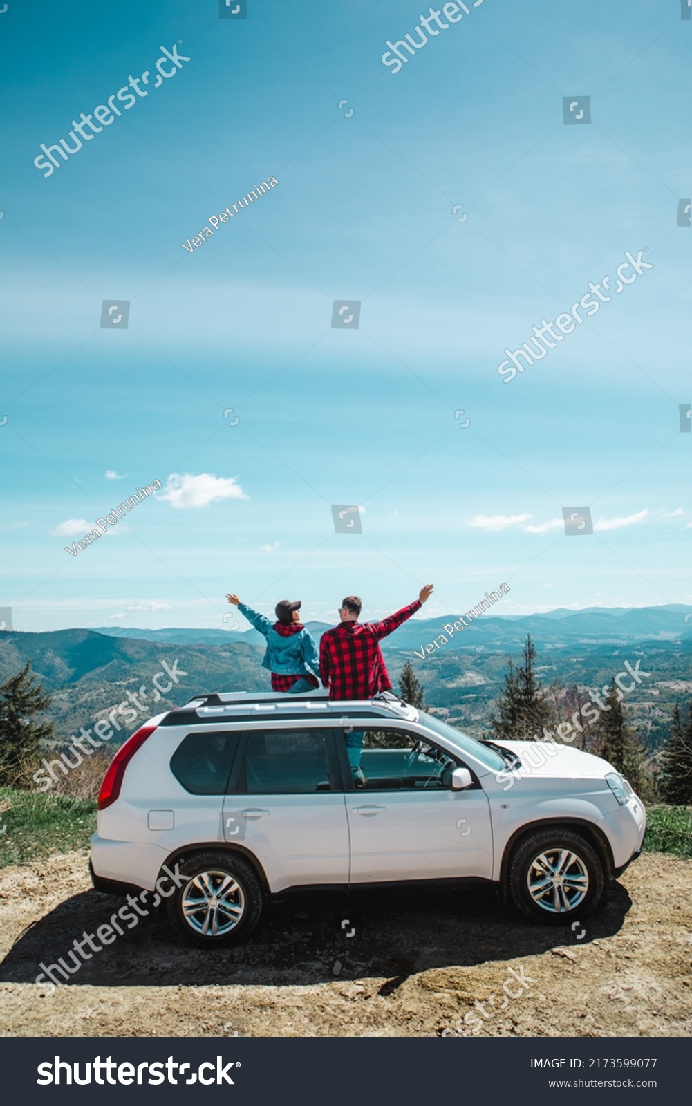 young woman sitting on the top of the suv car at mountain peak enjoying the landscape view at summer sunny day #2173599077