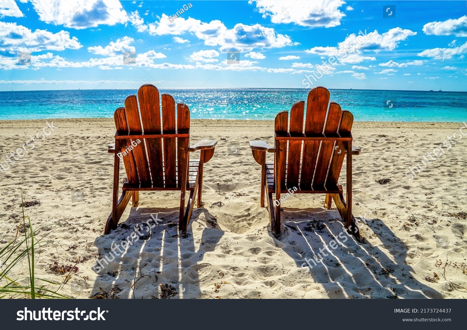 Two beach chairs on a sandy beach. Sandy beach scene. Two chairs on beach resort. Chairs on the beach #2173724437