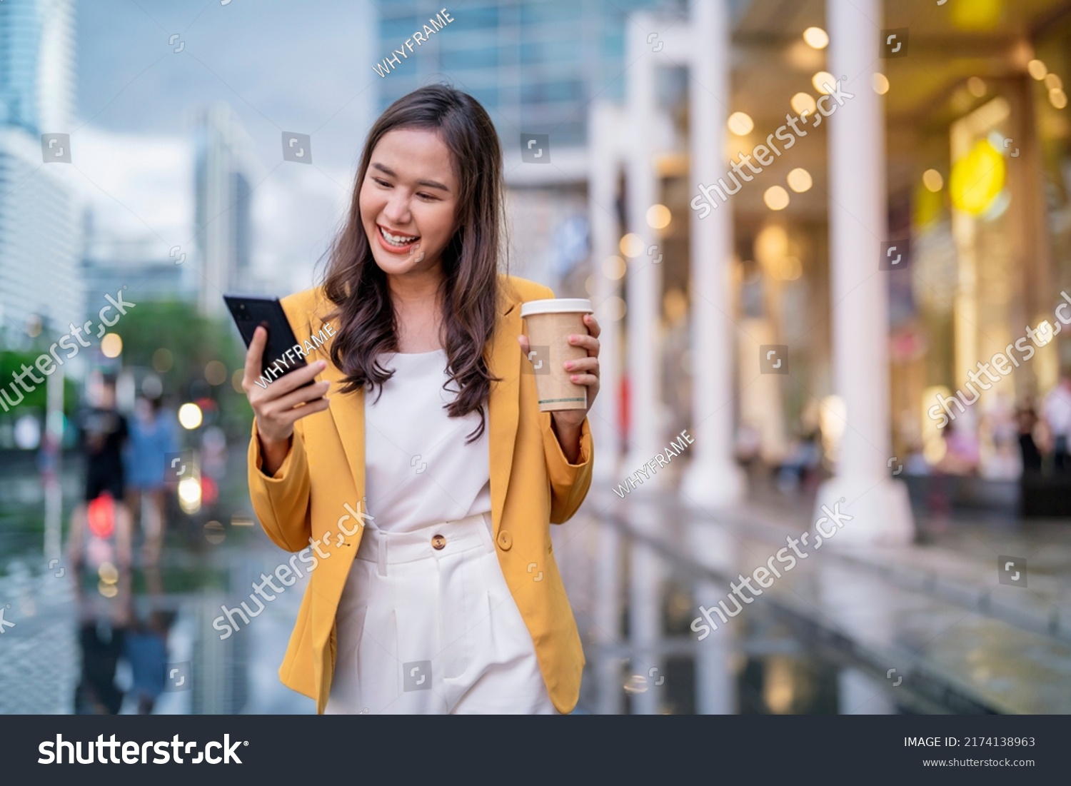 Urban modern lifestyle fashion portrait of asian young female stylish casual Asia woman walking 
with coffee cup and smartphone connection on the street, wearing cute trendy outfit after raining #2174138963