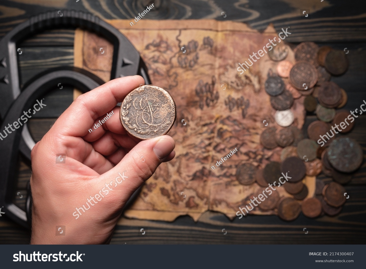 Ancient coin in treasure hunter hand close up on the metal detector, ancient coins and old treasure map background. Treasure hunting concept. #2174300407
