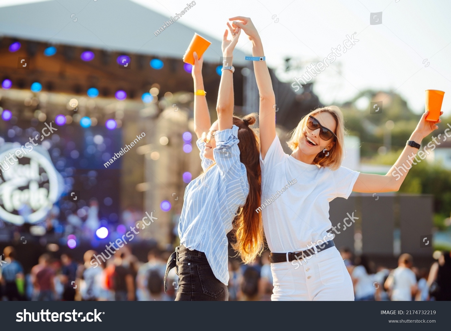 Two young woman drinking beer and having fun at Beach party together. Happy girlfriends  having fun at music festival. Summer holiday, vacation concept. #2174732219