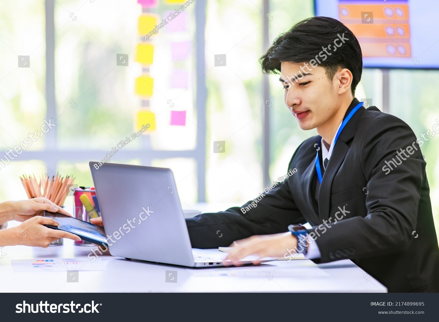 Asian young handsome professional success male businessman employee staff in formal suit sitting working with laptop notebook computer and paperwork graph chart growth target document in meeting room. #2174899695