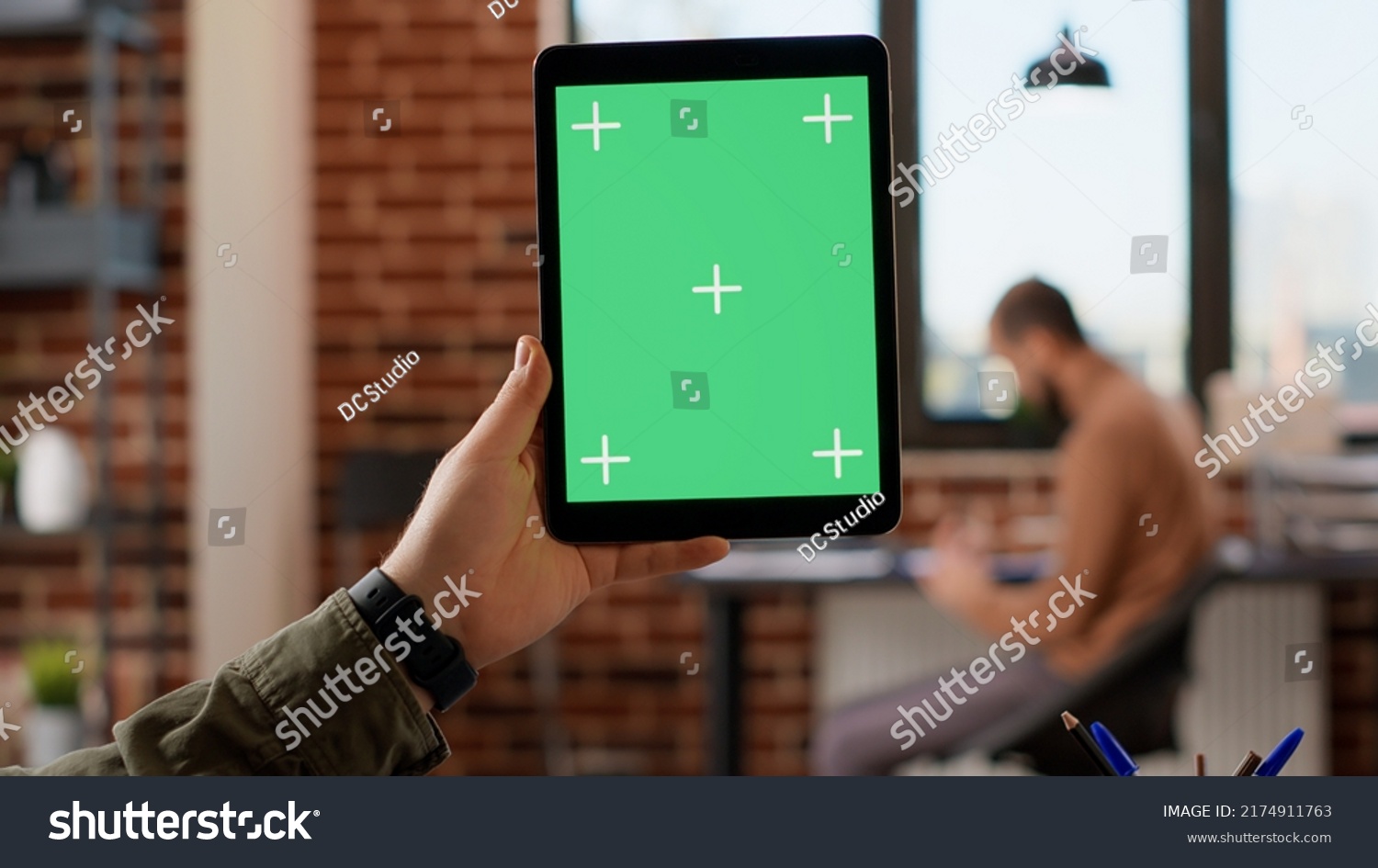 Company employee holding digital tablet with greenscreen in startup office, using isolated copyspace with mockup background and blank chroma key. Looking at digital web app on device. #2174911763