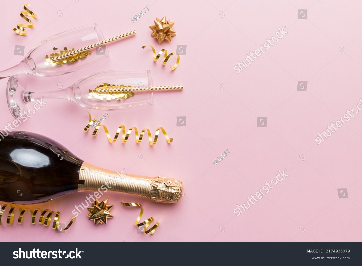 Champagne bottle, glitter and straws on color background. top view. Hilarious, christmas and birthday celebration. #2174935079