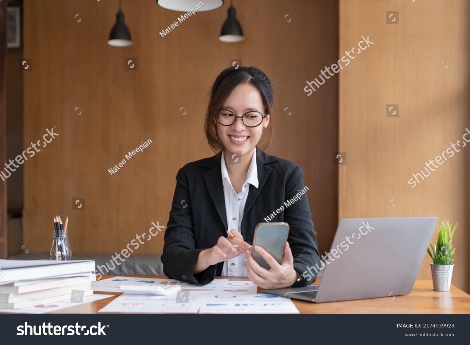 Asian woman holding smart phone while using calculator for business financial accounting calculate money bank loan rent payments manage expenses finances taxes doing paperwork concept, close up. #2174939923